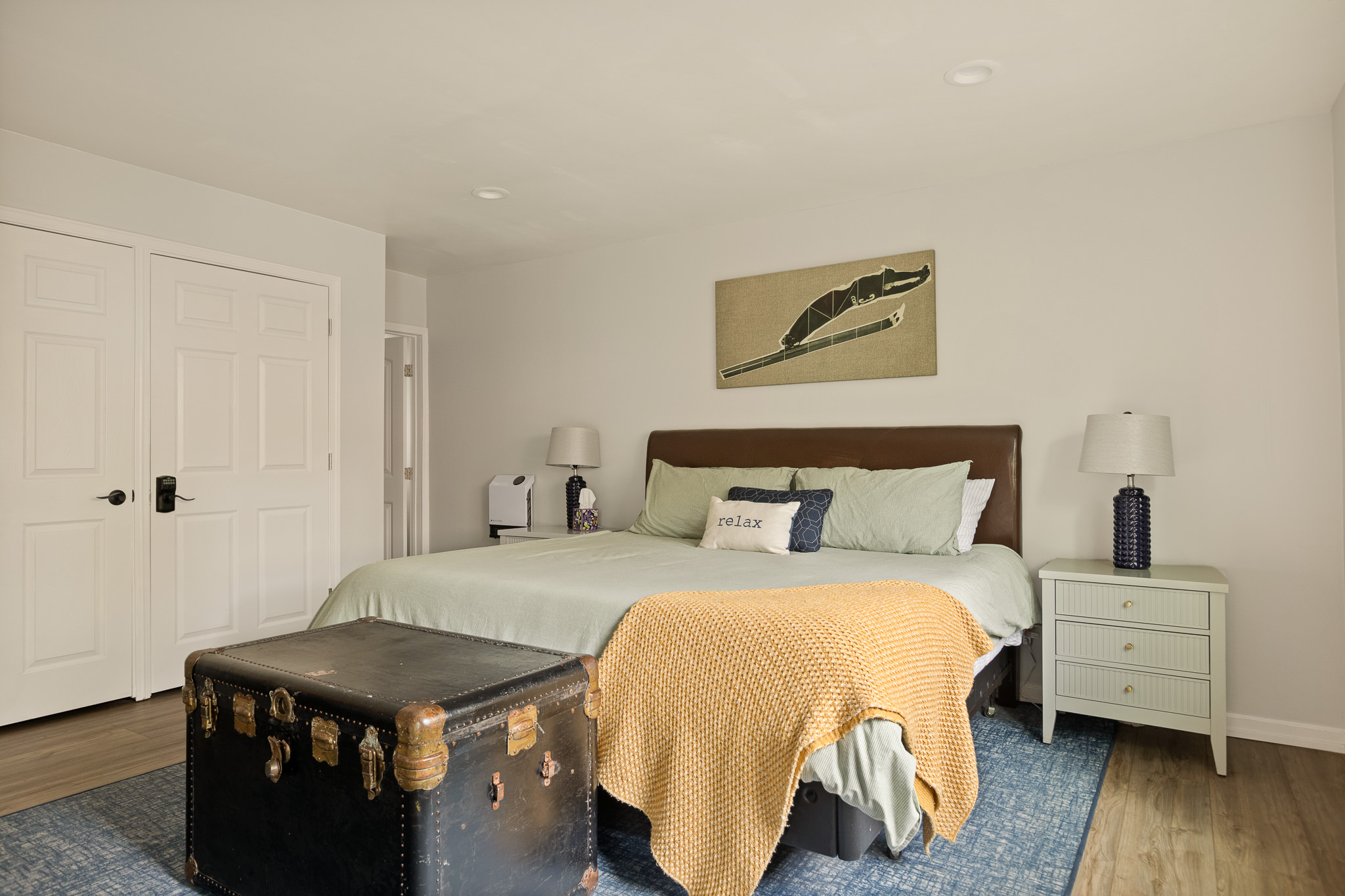 Second angle of the king bedroom with yellow throw and vintage trunk