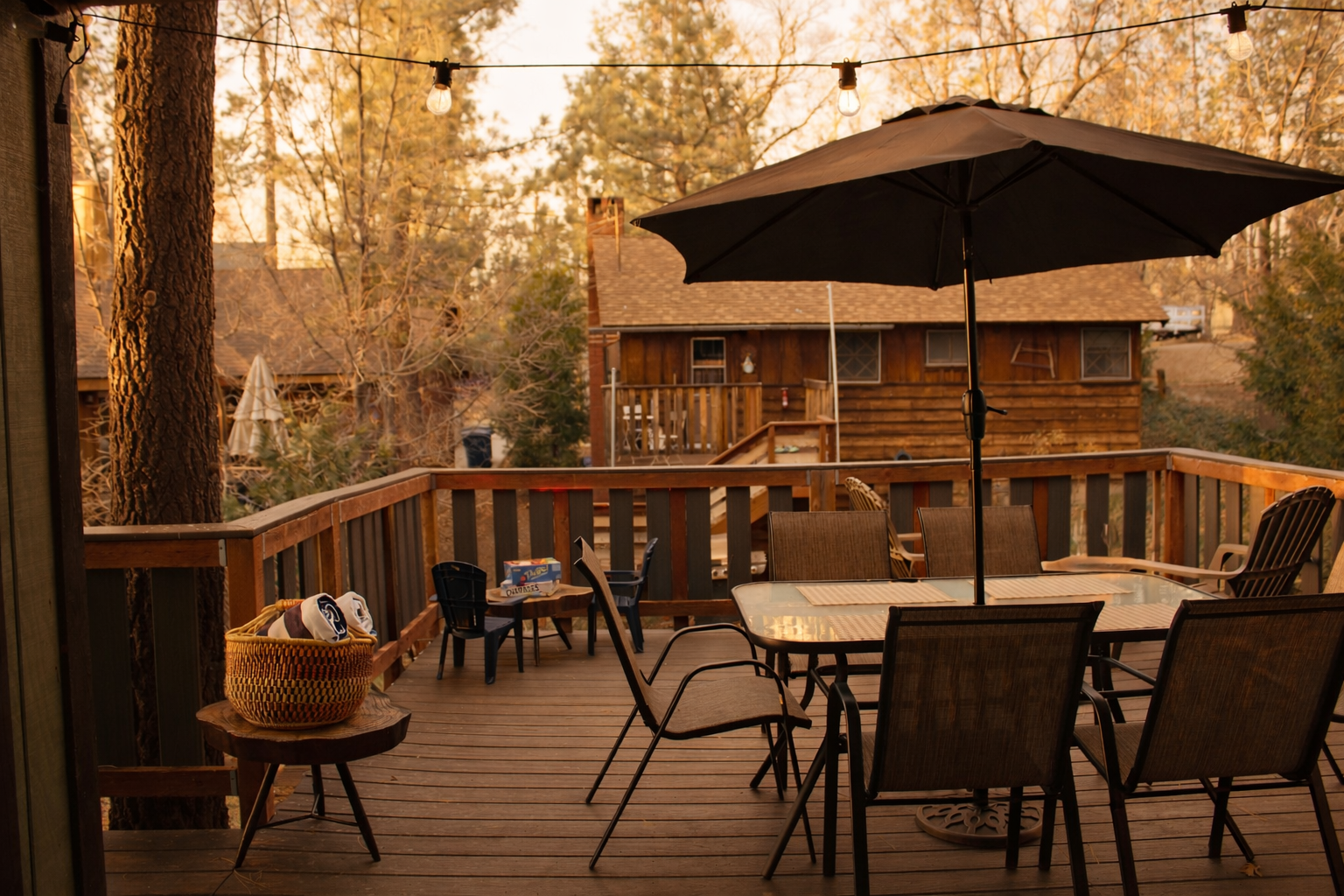 Outdoor dining deck with umbrella and string lights at dusk